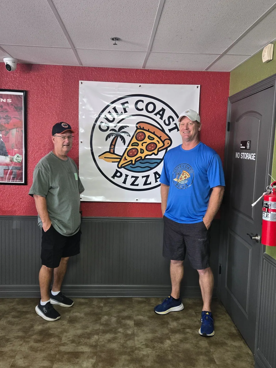 Two people beside the Gulf Coast Pizza restaurant sign